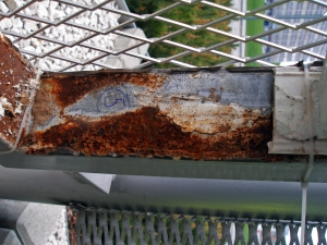 Obr. 2b: Příklad koroze žárově naneseného zinku na vnitřní straně ocelového rámu opatřeného montovanou výplní ze skleněných tvárnic s detailem zbytků korodující zinkové vrstvy