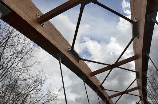 Dřevěné oblouky a táhla spojují vějířovitě uspořádané tyčové závěsy ze systémových prvků