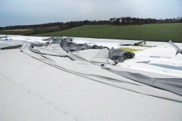 Obr. 7: Havárie plochých střech v důsledku námahy větrem – selhání kotvení okraje střechy bylo první fází selhání celé střechy