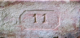 Plná cihla s kolkem 11 v osmibokém rámečku, běžný formát (290×140×65 mm), 1. polovina 20. století. U takto značených cihel je problematická přesná identifikace původu.