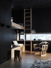 Kontrasty světel, materiálů a barev – úzká horizontální i vertikální okna přerušují černé dřevěné obložení interiéru