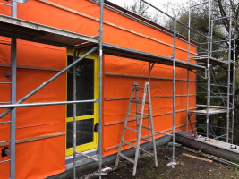 Ochrana zateplené fasády s obkladem s otevřenými spárami. Fotografie ze stavby v rozpracovaném stavu - barva jantarově oranžová (zdroj: Dörken)