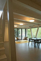 V interiérech je přiznaná konstrukce CLT panelů, prostor obývacího pokoje ozvláštňují šikmé pilíře a okno přetažené přes roh