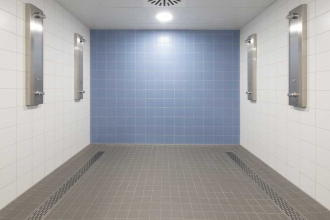 Centrální šatny a sprchy v nové tělocvičně. Dlaždice na podlahách jsou ze série Taurus ve formátu 30 x 30 cm a jsou doplněny mozaikami ve formátu 10 x 10 cm