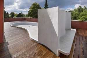Střešní terasa s organicky tvarovaným záhonem, větrolamem a lavičkou
