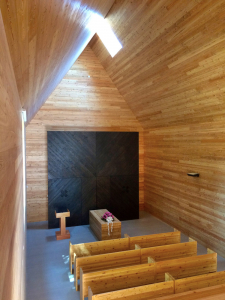 Interiér síně je obložený modřínovým dřevem, otevřený do krovu. Prosvětlují ho dvě velká okna.